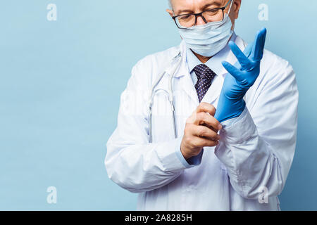 Arzt setzt auf Gummi Handschuhe, Gesundheitswesen und Medizin. Auf blauem Hintergrund isolieren Stockfoto