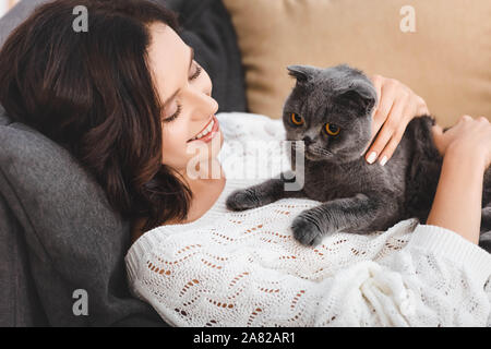 Schöne Frau auf Sofa mit Scottish Fold Katze Stockfoto