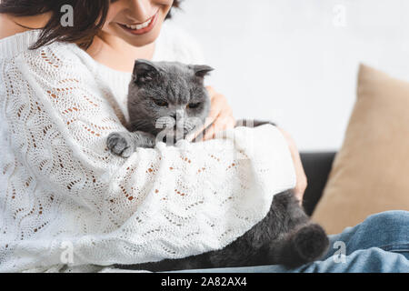 7/8-Ansicht von Happy schöne Frau sitzt auf einem Sofa mit Scottish Fold Katze Stockfoto