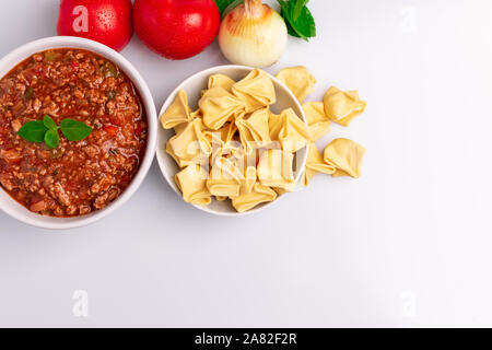 Fagottini Tortellini Nudeln mit Bolognese (auch bekannt als Bolognesa oder Bolonhesa) Soße in einer weißen Schüssel in weißem Hintergrund, weiches Licht, Studio Stockfoto