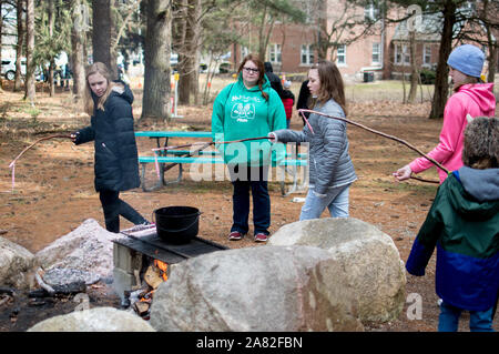 17. März 2019 Zucker camp Tage in Bendix woods Indiana USA; Mädchen lernen, wie man Hand das Abblendlicht Kerzen rund um ein Lagerfeuer aus geschmolzenem Wachs, mit Sticks Stockfoto