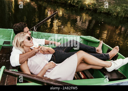 Glückliches junges Paar entspannend, während im Boot liegen auf See Stockfoto