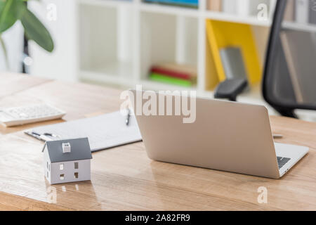Laptop, Haus Modell, Zwischenablage und Rechner auf hölzernen Tisch in Office Stockfoto