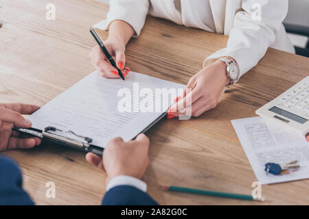 7/8-Ansicht des Geschäftsmannes holding Zwischenablage und Frau unterzeichnen Vertrag Stockfoto