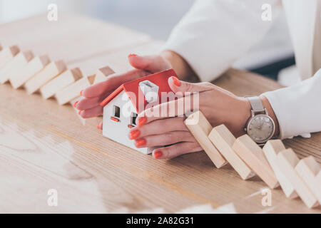 Der Risk Manager schützen Haus Modell von sinkenden Holzblöcke mit Händen 7/8 Stockfoto