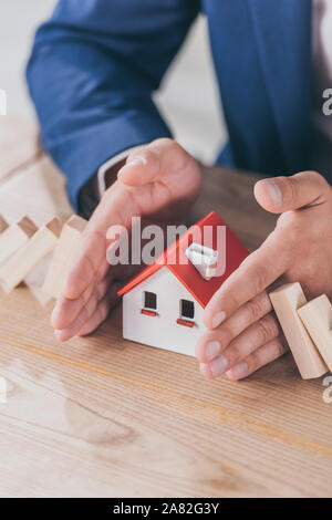 Der Risk Manager schützen Haus Modell von sinkenden Holzblöcke mit Händen 7/8 Stockfoto