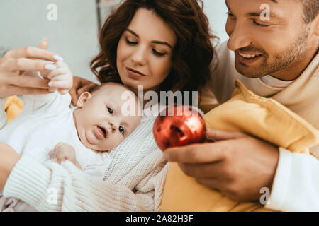 Gerne Vater übersicht Christmas Ball Cute Baby liegend auf Mütter Hände Stockfoto