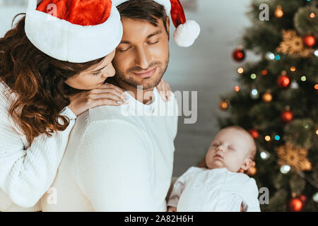 Glückliche Frau an schlafenden Baby über die Schulter der Mann sucht Stockfoto