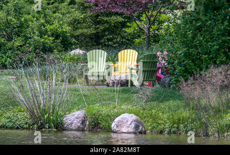 Bunte Adirondack Stühle durch die Waters Edge Stockfoto