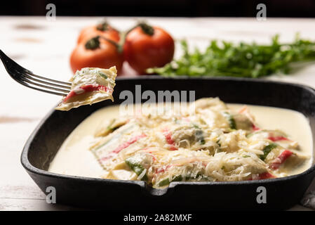 Handgefertigt Farbe ravioli Pasta; Mehrfarbige ravioli Pasta in einem schwarzen eiserne Pfanne, auf weißem Hintergrund. Stockfoto