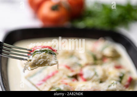 Handgefertigt Farbe ravioli Pasta; Mehrfarbige ravioli Pasta in einem schwarzen eiserne Pfanne, auf weißem Hintergrund. Stockfoto