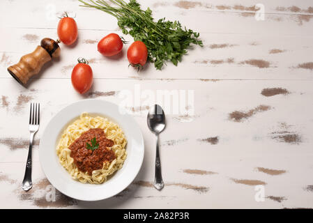 Fettuccine Pasta Bolognese mit Tomatensauce in eine weiße Platte auf rustikalen Holztisch Hintergrund, weiches Licht Stockfoto