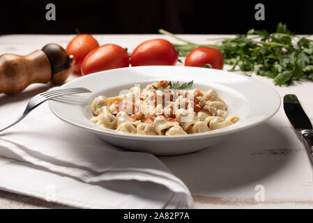 Italienisch Tortellini (capeletti, Agnolini) mit Tomatensauce in eine weiße Platte auf rustikalen Holztisch Hintergrund weiss Stockfoto