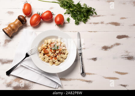 Italienisch Tortellini (capeletti, Agnolini) mit Tomatensauce in eine weiße Platte auf rustikalen Holztisch Hintergrund weiss Stockfoto