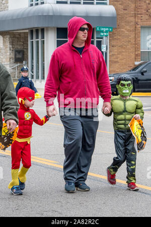 Oktober 27, 2018 Coloma MI USA; ein Vater hält die Hände von zwei super Helden, wie Sie gehen die Straße hinunter, während ein Halloween event Stockfoto