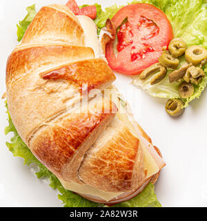 Croissant Sandwich mit Salat, Schinken, Käse, Tomaten und Oliven auf Holz- Hintergrund. Frühstück Konzept. Gesund und Fast Food. Isoliert. Stockfoto