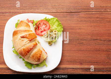 Croissant Sandwich mit Salat, Schinken, Käse, Tomaten und Oliven auf Holz- Hintergrund. Frühstück Konzept. Gesund und Fast Food. Isoliert. Stockfoto