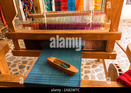 Detail einer Holz- Weberei Shuttle auf den gewebten Tuch auf einem Fuß betätigten Holz- Webstuhl in San Antonio Palopó, Guatemala. Stockfoto