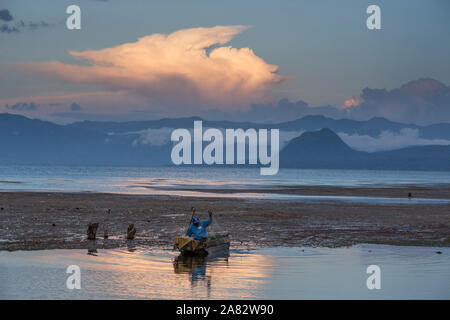 Ein Fischer zieht sein Netz in seine cayuco bei Sonnenuntergang am Lake Atitlan, Guatemala. Im Hintergrund ist der Cerro del Oro und das Ostufer des Sees. Stockfoto