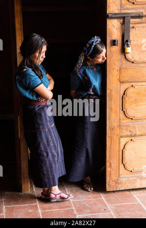 Zwei Maya-frauen Peer aus der Tür des Heiligen Antonius von Padua Kirche in San Antonio Palopó, Guatemala, tragen typische Kleid ihres Dorfes, inclu Stockfoto