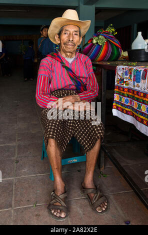 Eine 80-jährige Maya Bauer sitzt in den Markt in San Antonio Palopó, Guatemala, tragen die typische Kleid seiner Stadt, einschließlich einer hand-woven Shirt. Stockfoto