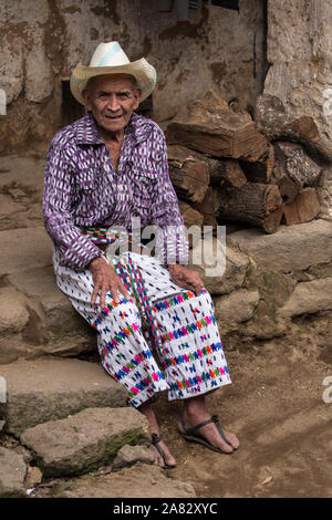 90 Jahre sitzt alte Maya-Mann in traditioneller Kleidung auf die grobe Steinstufen von seinem Haus in San Pedro la Laguna, Guatemala. Stockfoto