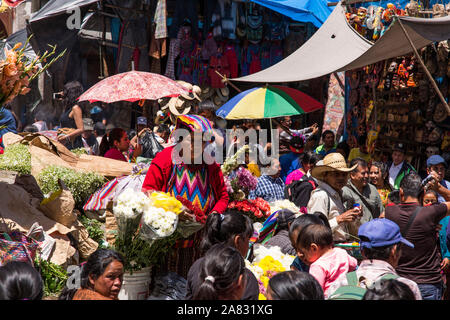 Massen von Menschen kommen aus den umliegenden Städten der Markt am Sonntag in Chichicastenango, Guatemala zu besuchen. Eine Quiche Maya Frauen verkauft Blumen. Stockfoto