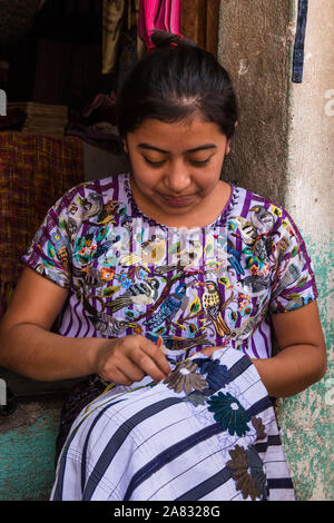 Ein Maya Frau in traditioneller Kleidung stickt ein traditionelles huipil Bluse in Santiago Atitlan, Guatemala. Stockfoto