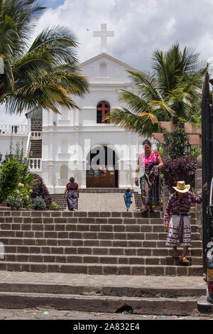 Eine ältere Maya Mann und eine Frau im mittleren Alter Maya, sowohl in traditioneller Kleidung, gehen Sie die Treppe hinunter auf den Platz vor der Kirche von San Pedro in Stockfoto