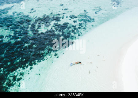 Frau Schnorcheln mit vielen kleinen Haie in der Nähe von White Sand Beach in Türkis sauberes Wasser. Drone Luftaufnahme. Tropischen Hintergrund und Travel Concept Stockfoto