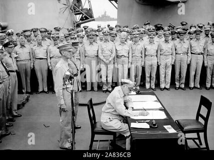 General Douglas MacArthur Zeichen als Oberster Alliierter Befehlshaber während der formalen Übergabe Zeremonien auf der USS Missouri in der Bucht von Tokio. Hinter General MacArthur sind Generalleutnant Jonathan Wainwright und Generalleutnant A.E. Percival. September 2, 1945 Stockfoto