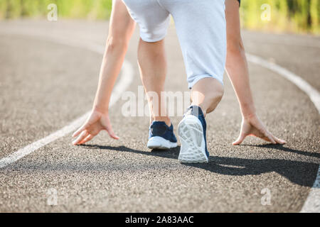 Sportlicher junger Mann in Crouch position Start im Stadion Stockfoto