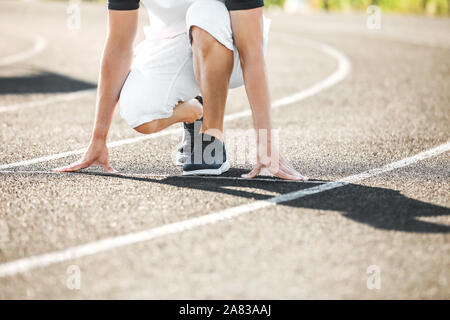 Sportlicher junger Mann in Crouch position Start im Stadion Stockfoto