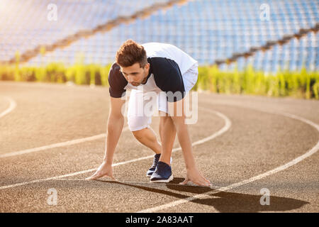 Sportlicher junger Mann in Crouch position Start im Stadion Stockfoto