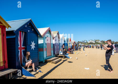 MELBOURNE, AUSTRALIEN - 31 AUGUST, 2019: Touristen fotografieren am berühmten Strand von Brighton mit bunten Baden Boxen Stockfoto