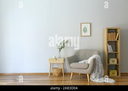 Stilvolles Interieur der Zimmer mit Sessel und Eukalyptus Zweige in der Vase auf dem Tisch Stockfoto