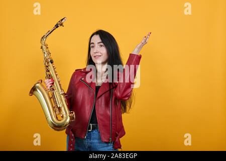 Wütend, wütend traurig wütend junge Frau in Jeans posiert, gold Saxophon Stockfoto