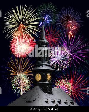 Die Uhr auf dem Rathausturm zeigt, Mitternacht, den Hintergrund festlichen Feuerwerk. Ein farbenfrohes Feuerwerk um Mitternacht das Neue Jahr zu feiern. Stockfoto