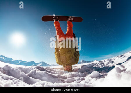 Snowboarder steht mit der Oberseite nach unten auf Kopf gegen Berge. Ski Konzept Stockfoto