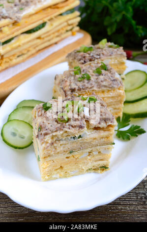 Layer Cake mit Eiern, Käse, grüne Zwiebeln, Fischkonserven, Mayonnaise auf einem weißen Teller auf einen hölzernen Tisch. Festliche Vorspeise. Stockfoto