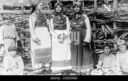 Fotos zeigen drei alte Frauen in kulturellen Kleid stand vor der Gebäude und die vier Jungs vor Zaun anmelden. Russland 1880-1924 Stockfoto