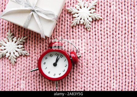 Flach Weihnachten Komposition mit Wecker, Geschenkbox und Weihnachtsschmuck auf rosa Hintergrund gestrickt. Stockfoto