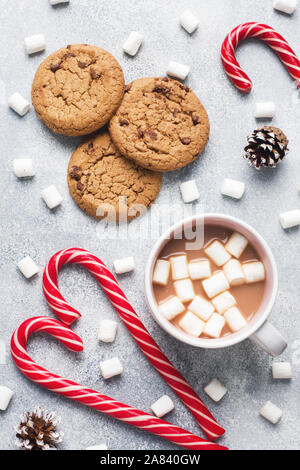 Die Chocolate Chip Cookie, Weihnachten Zuckerrohr Karamell Tasse Kakao und Marshmallow kegel Dekorationen auf grauem Hintergrund Nahaufnahme Stockfoto