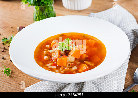Tomate Hühnersuppe mit Kürbis und weiße Bohnen in weiße Schüssel. Stockfoto
