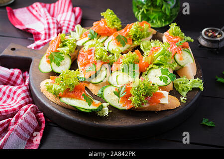 Tapas. Gesalzenen Lachs, Butter und Gurken toast Sandwiches auf Holzbrett. Stockfoto