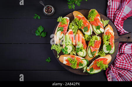 Tapas. Gesalzenen Lachs, Butter und Gurken toast Sandwiches auf Holzbrett. Ansicht von oben Stockfoto