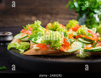 Tapas. Gesalzenen Lachs, Butter und Gurken toast Sandwiches auf Holzbrett. Stockfoto