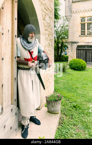 Outdoor Pose eines Mannes in authentischen Templer Outfit oder kreuzritter Kostüm stehen vor dem Hintergrund eines mittelalterlichen französischen Schloss gekleidet Stockfoto