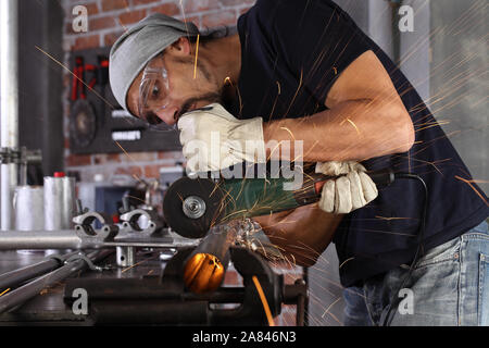 Mann Arbeit in Home Werkstatt garage cut Metall Rohr, Schutzbrille und Handschuhe, Schneiden von Metall macht Funken, Nahaufnahme, Heimwerker- und craft-Konzept Stockfoto