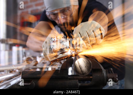 Mann Arbeit in Home Werkstatt garage mit Winkelschleifer, Schutzbrille und Handschuhe, Schleifen von Metall macht Funken, Nahaufnahme, Heimwerker- und craft-Konzept Stockfoto